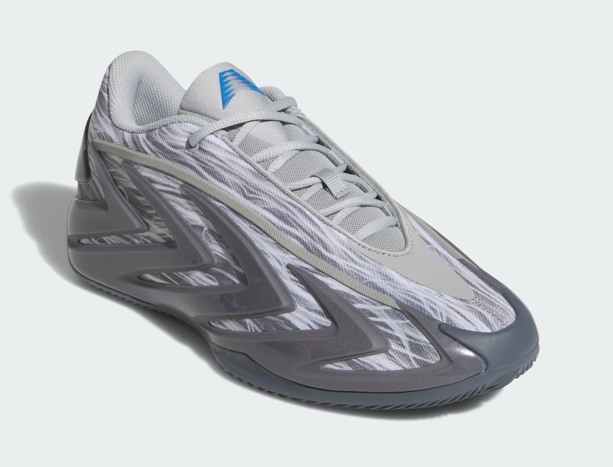 adidas Anthony Edwards 3 Snow Camo en vista de tres cuartos, con el camuflaje gris y blanco, los cordones grises y el logo AE azul en la lengüeta