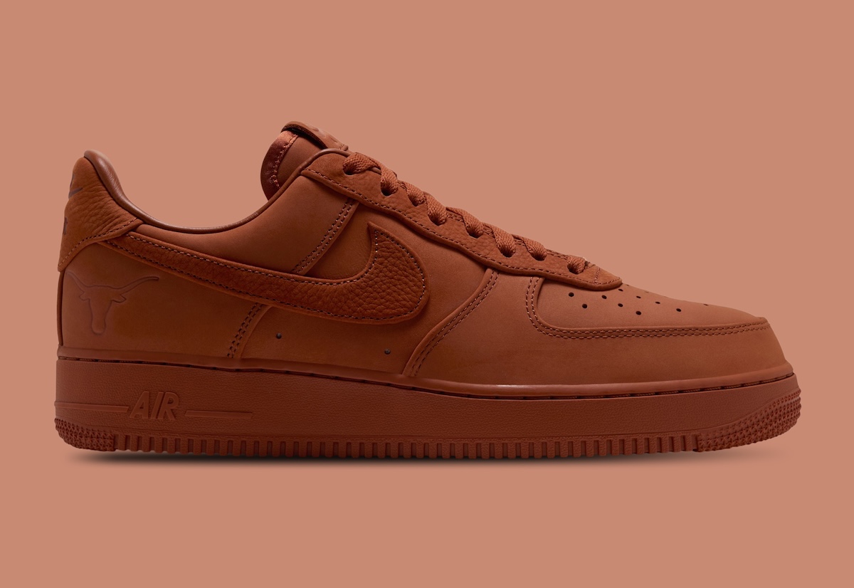 Nike Air Force 1 Low Luxe de la Universidad de Texas de perfil lateral sobre fondo terracota, entero en naranja tostado de la capellada a la suela, con el Swoosh de textura granulada y la cabeza de longhorn grabada en el talón
