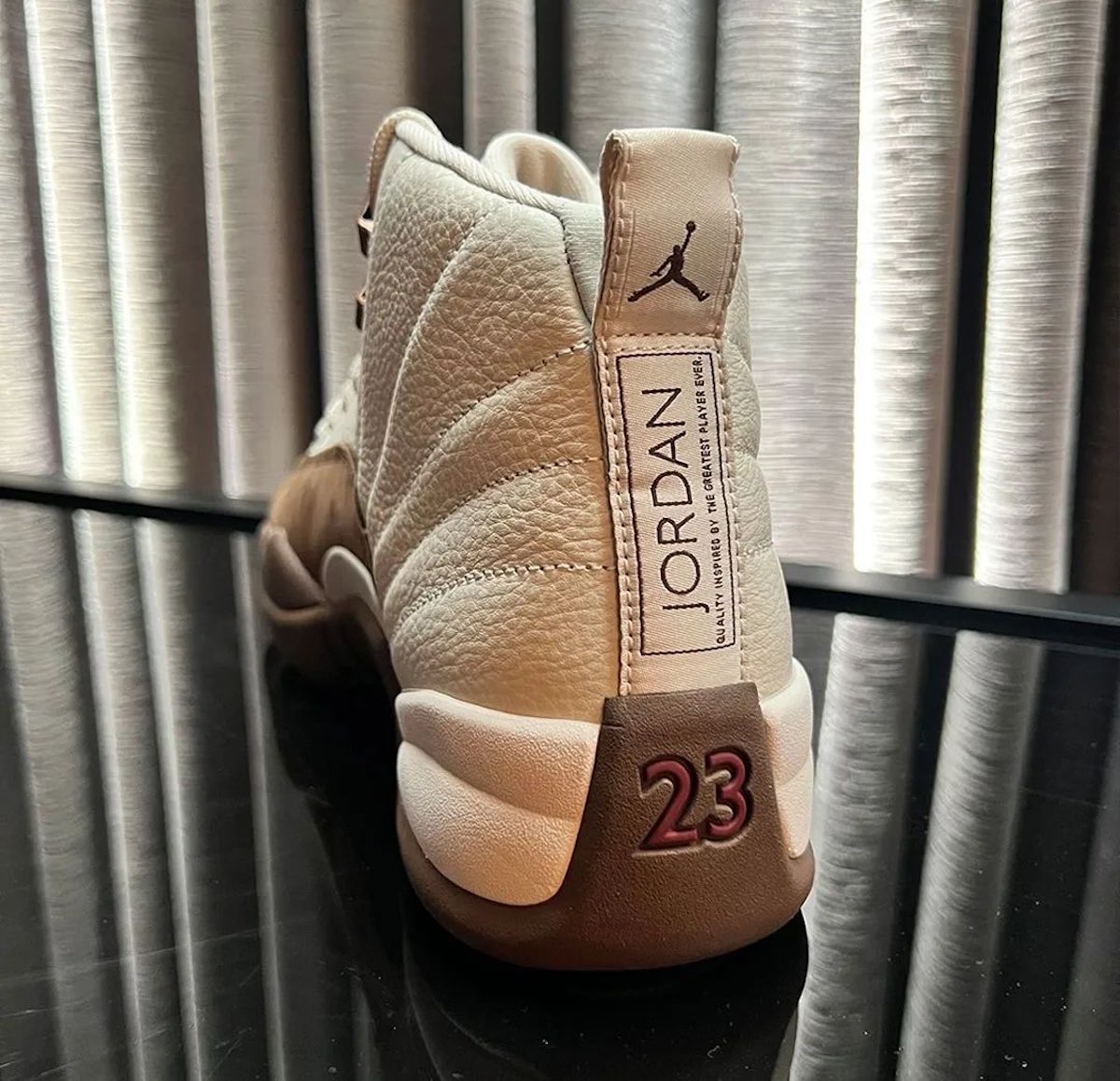 Talón del Air Jordan 12 Fireside con el tirador claro, la etiqueta Jordan y el 23 en rojo sobre la base marrón