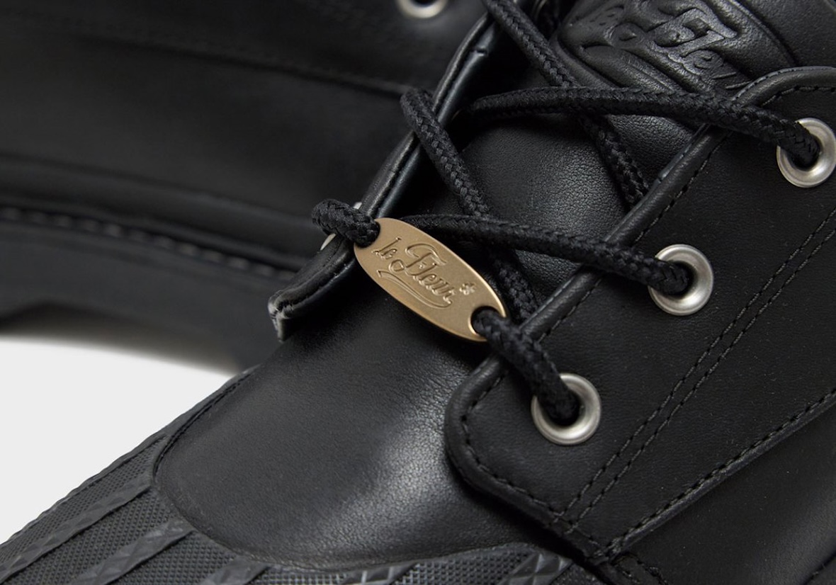 Primer plano del Converse 1908 Bronco Boot Low negro con la plaqueta dorada le FLEUR en los cordones, los ojales metálicos y el logo grabado en la lengüeta