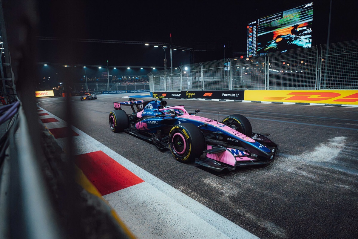 El Alpine número 43 de Franco Colapinto, azul y rosa, dobla de noche pegado al piano en el circuito de Marina Bay durante la carrera