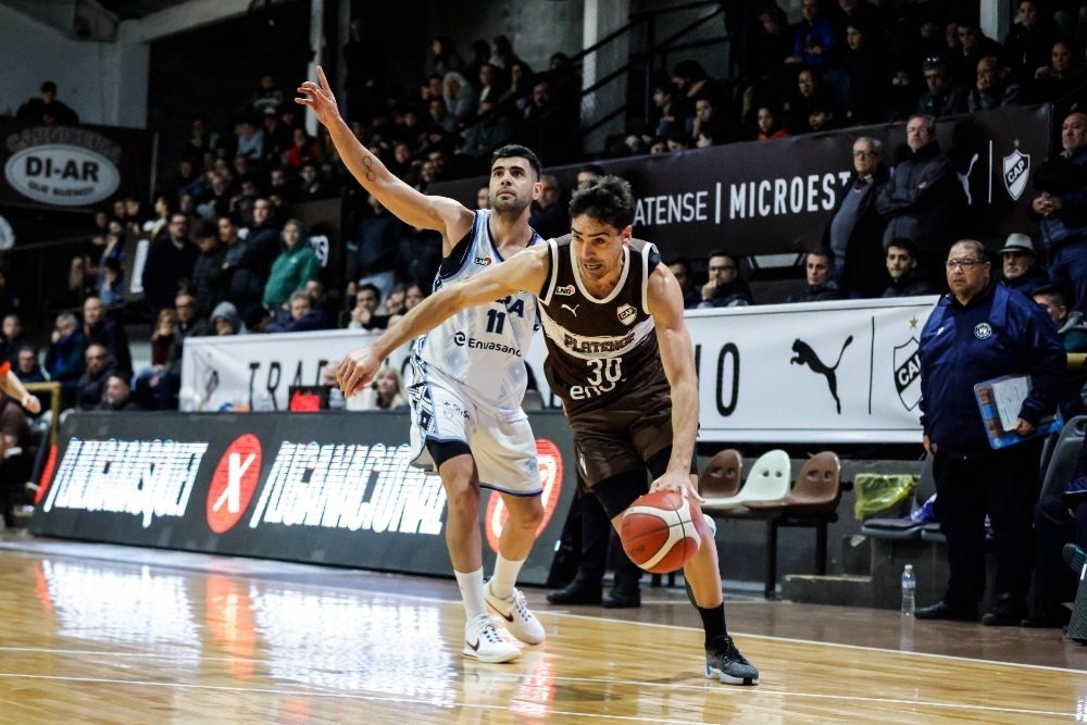 Mauro Cosolito, de Platense, con la camiseta marrón número 30, avanza con la pelota ante la marca de Agustín Brocal, de Oberá, con la camiseta blanca número 11, en el Microestadio Ciudad de Vicente López