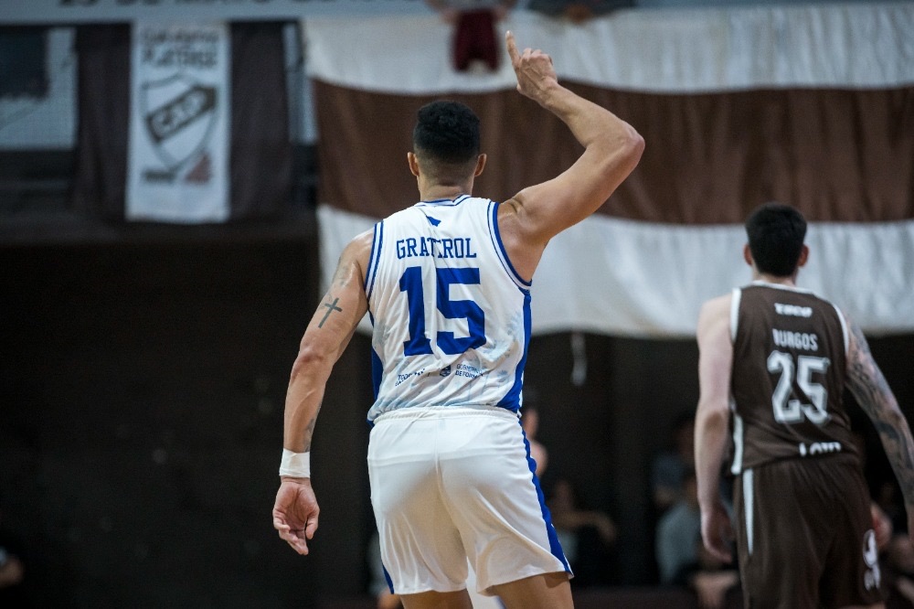 Windi Graterol, de La Unión de Formosa, de espaldas con la camiseta blanca 15, levanta el brazo derecho; a su lado, un jugador de Platense con la camiseta marrón 25