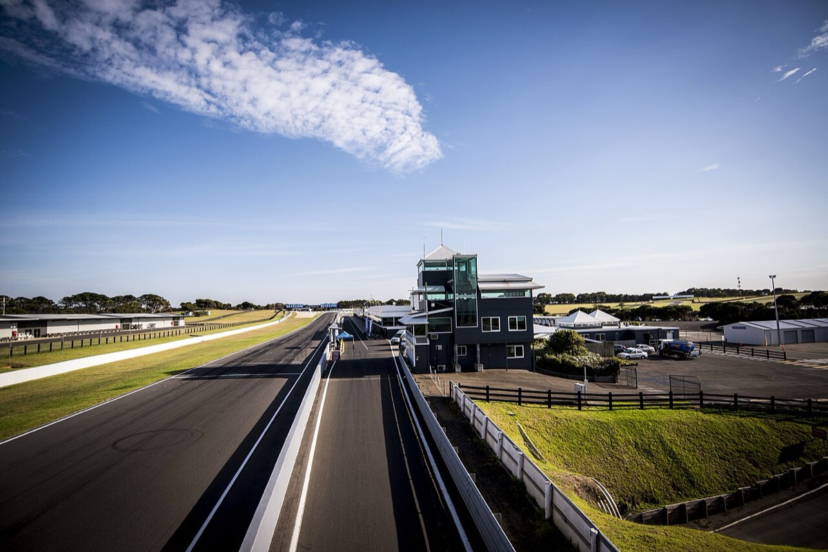 Foto de archivo: la recta principal de Phillip Island vacía, con la torre de control a la derecha y el cielo azul con una nube larga