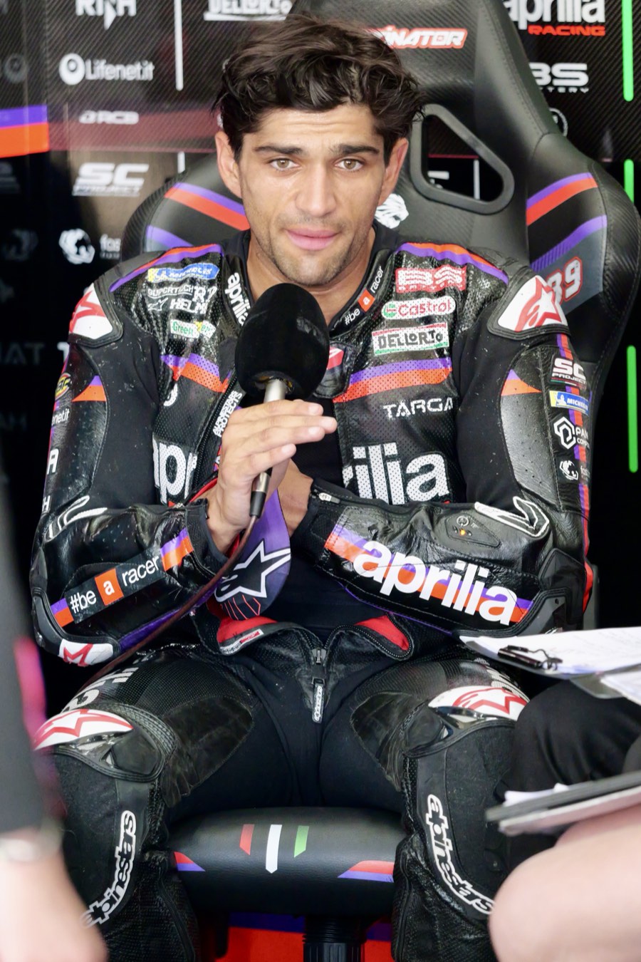 Foto de archivo: Jorge Martín, con el buzo negro de Aprilia Racing, habla sentado en el box con un micrófono en la mano