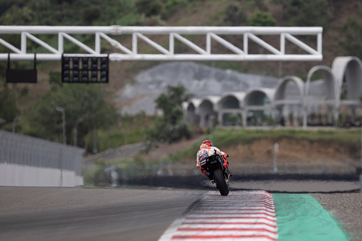 Foto de archivo: un piloto con la moto naranja y blanca encara la recta principal de Mandalika, con el semáforo de largada y las tribunas de techos curvos de fondo