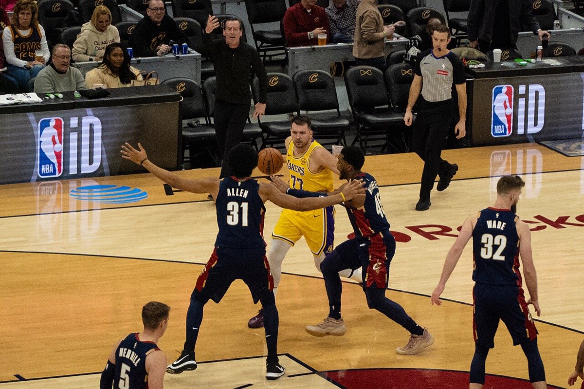 Luka Doncic, con la camiseta amarilla número 77 de los Lakers, recibe la marca de Jarrett Allen y Donovan Mitchell en un partido en Cleveland