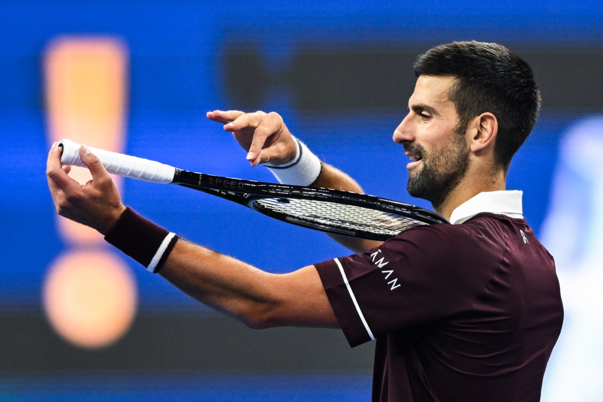 Novak Djokovic, de remera bordó, mira y acomoda su raqueta con las dos manos en la cancha del China Open 2026, durante su partido de cuartos de final