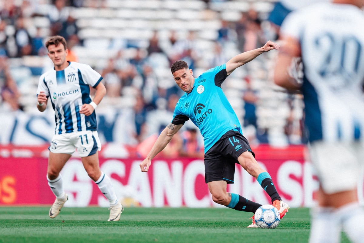 Un mediocampista de Belgrano le pega a la pelota ante la marca de un jugador de Talleres en el Kempes (foto: prensa Club Atlético Belgrano)