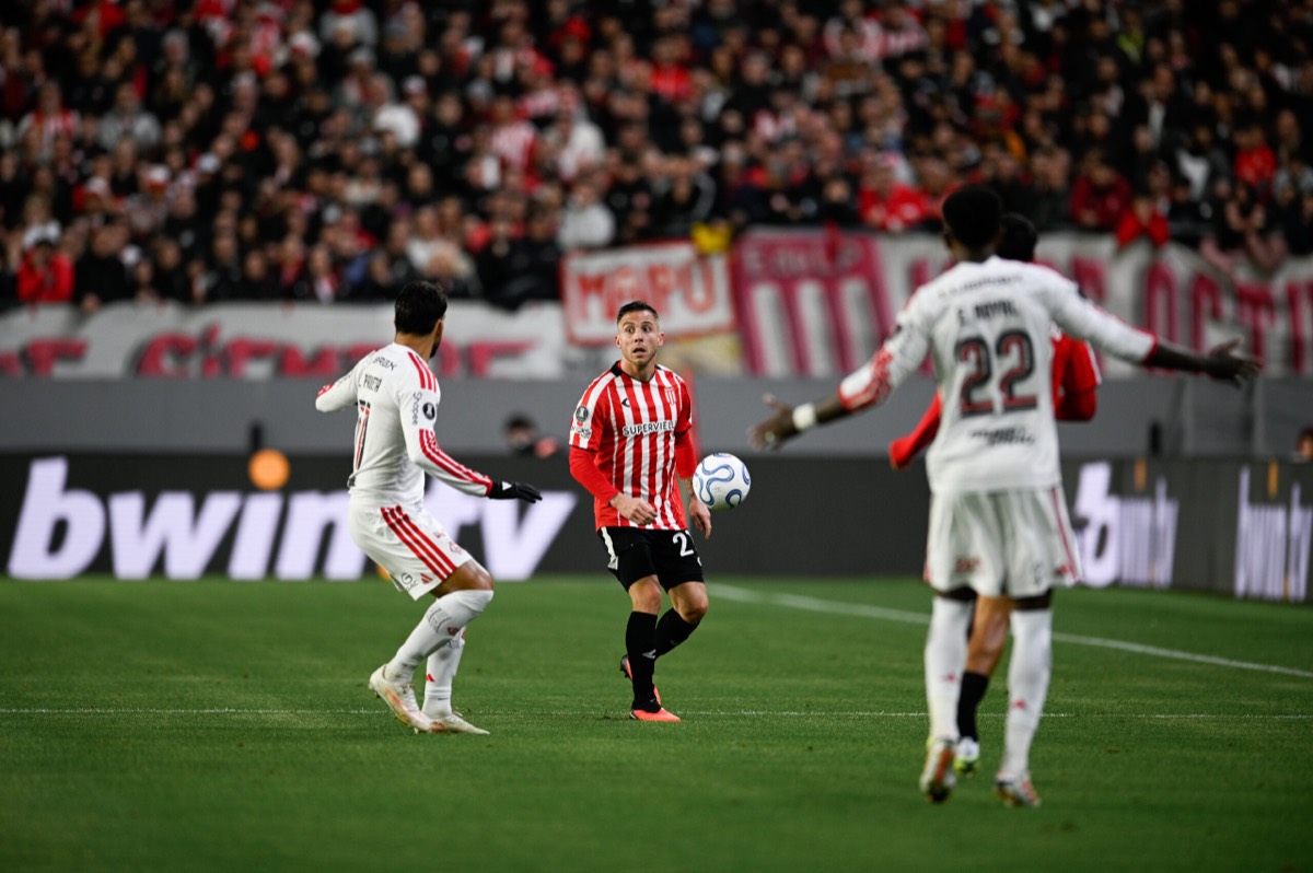 Un jugador de Estudiantes, con la camiseta albirroja, controla la pelota entre futbolistas de Flamengo de blanco, entre ellos Emerson Royal con el número 22, en el estadio UNO de La Plata durante la ida de la semifinal de la Libertadores (foto: prensa oficial de Estudiantes de La Plata)