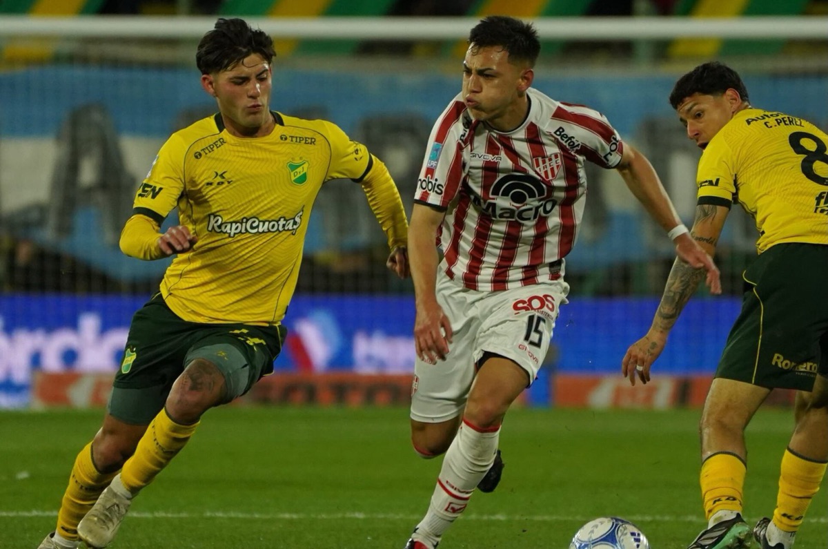 Un jugador de Instituto conduce la pelota entre dos futbolistas de Defensa y Justicia en el estadio Norberto Tomaghello, durante el partido de la fecha 13 del Torneo Clausura 2026 (foto: prensa Defensa y Justicia)
