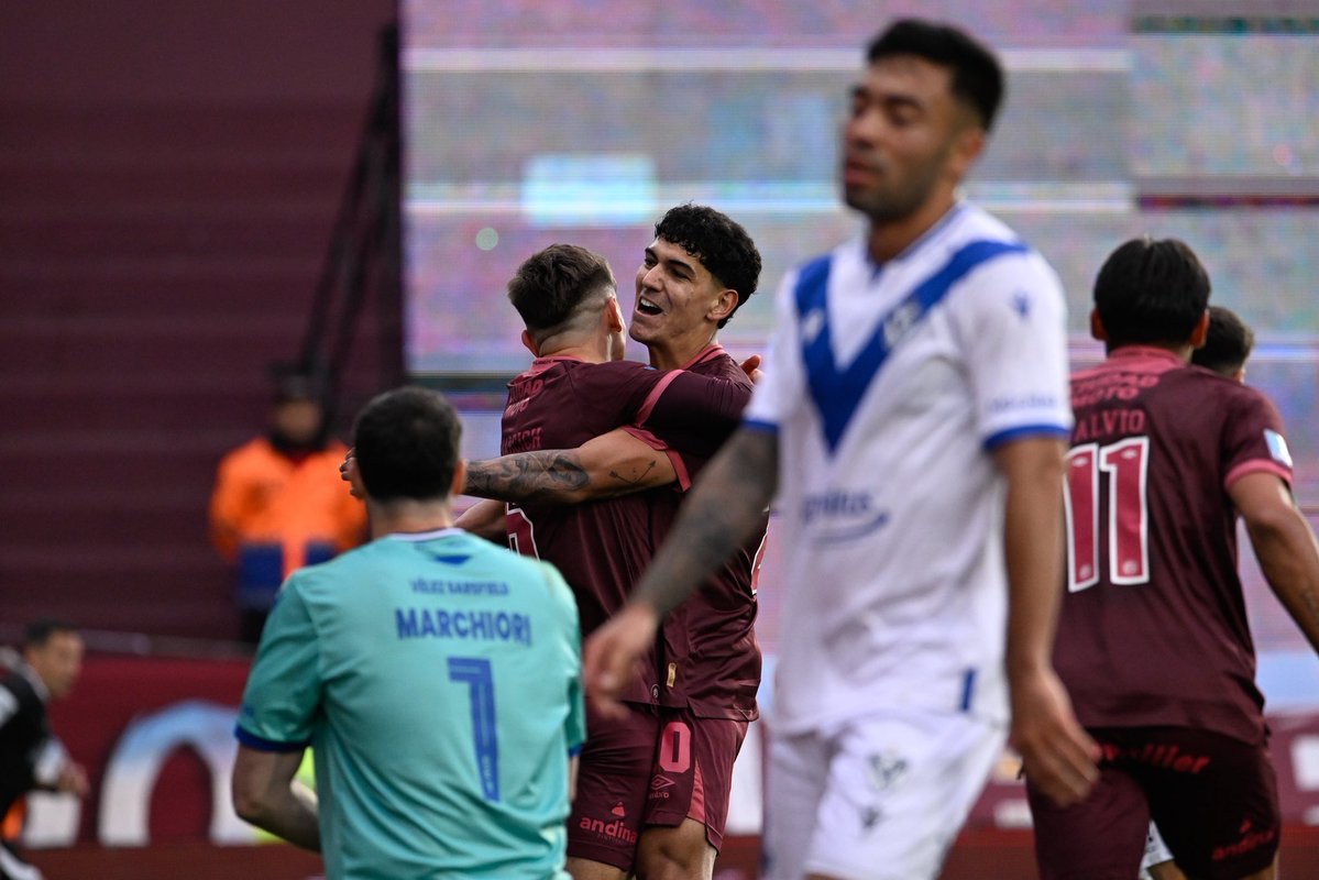 Los jugadores de Lanús, con la camiseta granate, se abrazan en el festejo del primer gol ante Vélez, con el arquero Tomás Marchiori de espaldas y un jugador de Vélez en primer plano (foto: prensa Club Atlético Lanús)