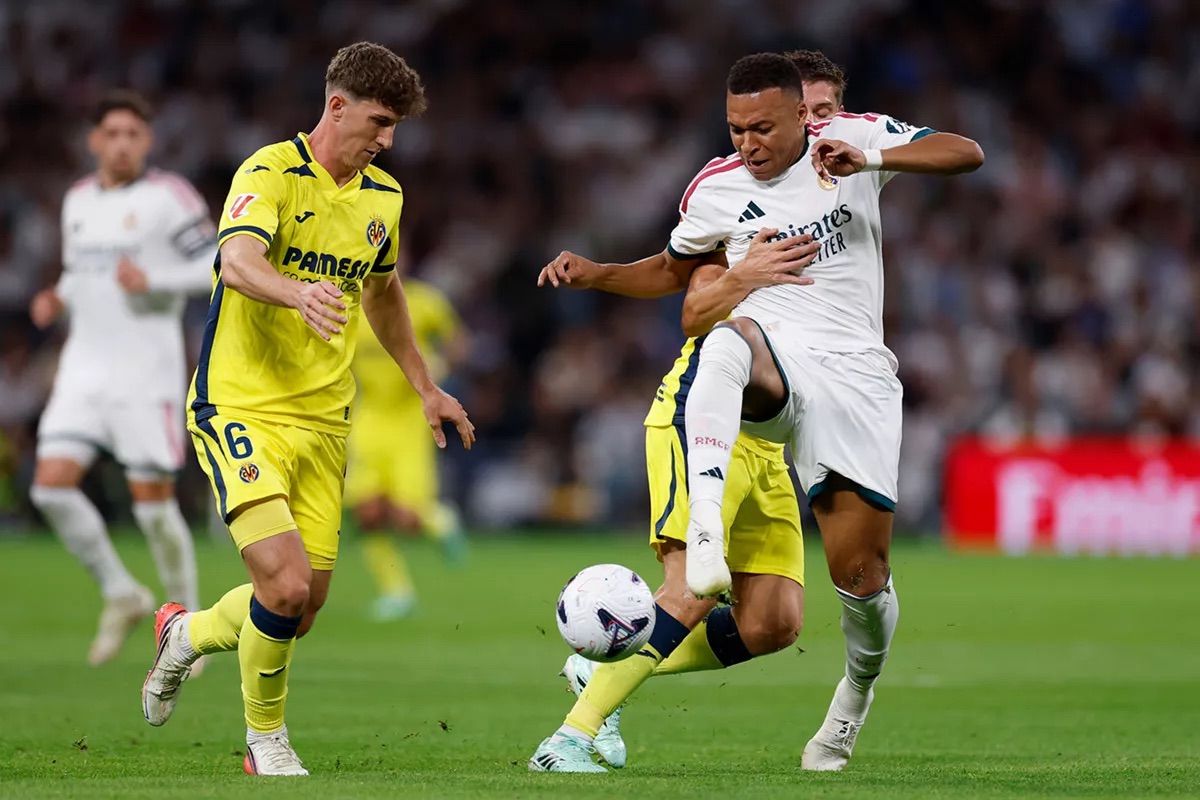 Kylian Mbappé protege la pelota entre dos jugadores del Villarreal, de camiseta amarilla, durante el partido en el Bernabéu (foto: Real Madrid C.F.)