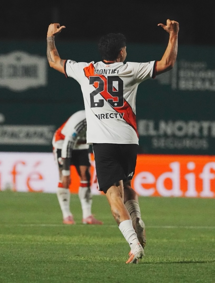 Gonzalo Montiel, de espaldas con la camiseta blanca de la banda roja, el número 29 y su apellido, levanta los brazos para festejar su gol a Sarmiento en el estadio Eva Perón de Junín (foto: prensa River Plate)