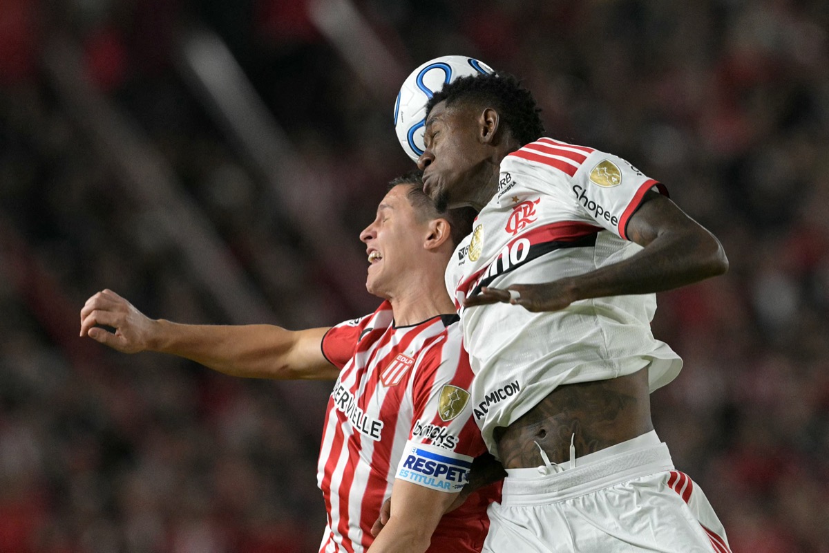 Un jugador de Estudiantes y uno de Flamengo saltan a cabecear la misma pelota en un cruce de la Copa Libertadores