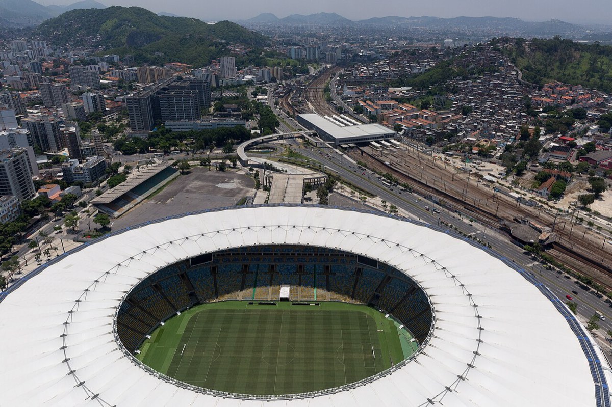 Vista aérea del estadio Maracaná de Río de Janeiro, con su techo blanco alrededor de las tribunas y el campo de juego, y la ciudad y los cerros de fondo; foto de archivo de diciembre de 2016 (foto: Diego Baravelli, Wikimedia Commons, licencia CC BY-SA 4.0)