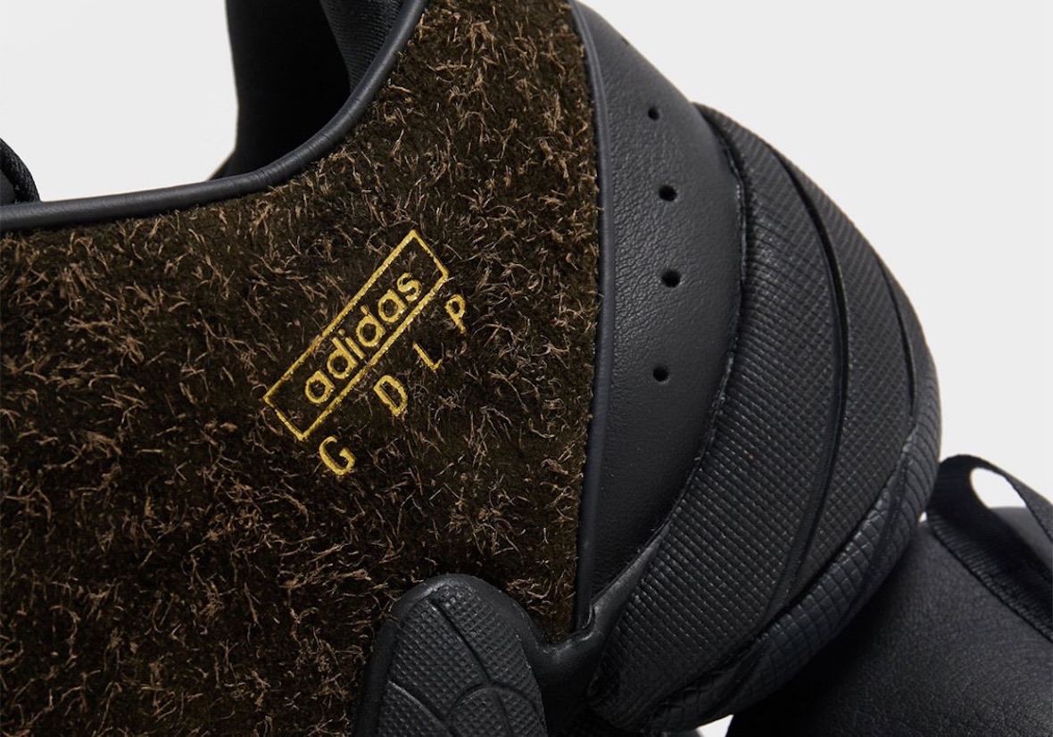 Detalle del lateral de la Guadalupe x adidas Intimidation con el logo adidas y las letras GDLP en dorado sobre la gamuza de pelo largo y la pieza negra del talón