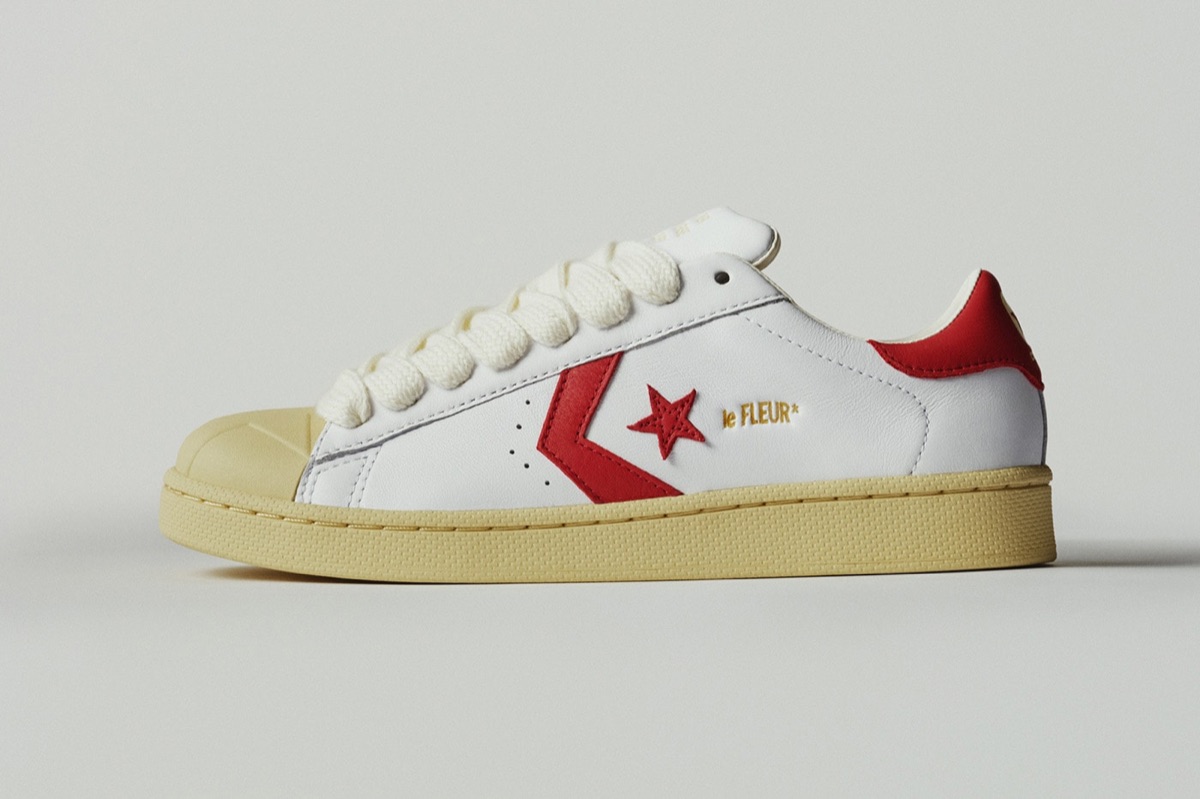 Converse Pro Leather blanca de GOLF le FLEUR* de perfil sobre fondo gris claro, con cuero blanco, la estrella y el chevron rojos, talón rojo, cordones gruesos color crudo y puntera de goma