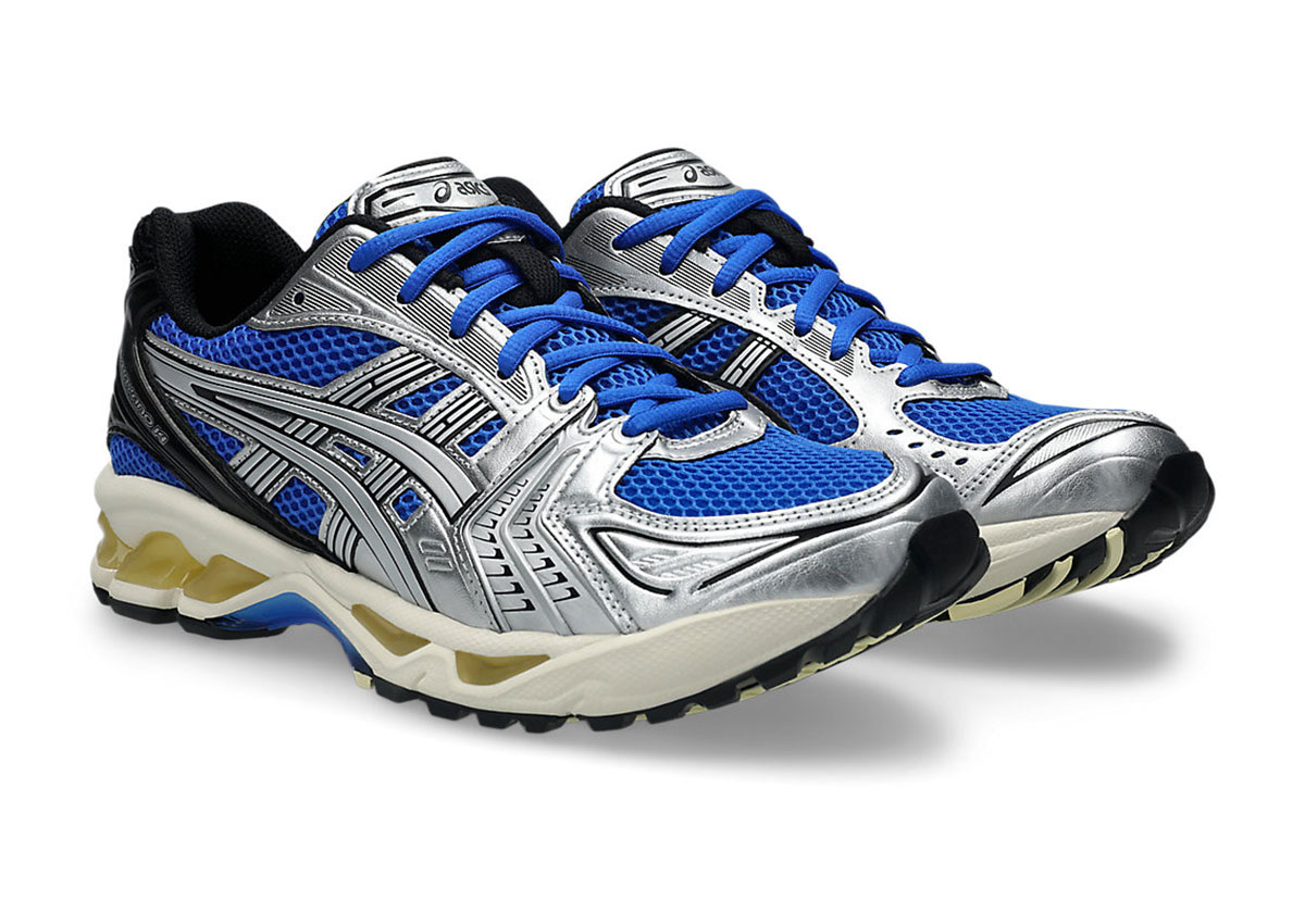 Par de ASICS GEL-Kayano 14 Illusion Blue Pure Silver en diagonal sobre fondo blanco, con malla azul eléctrico, capas plateadas metalizadas, cordones azules, talón negro y mediasuela crema con GEL amarillento