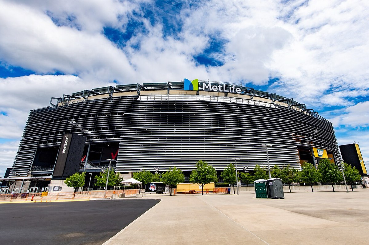Fachada del MetLife Stadium de East Rutherford, Nueva Jersey, con su revestimiento de láminas metálicas y el cartel de MetLife arriba, en un día de cielo con nubes. Foto: Thecoolone1223, Wikimedia Commons, CC BY 4.0