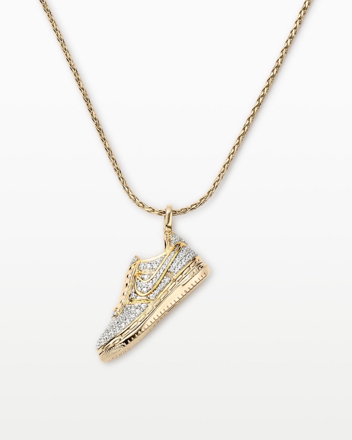 Collar Nike Air Force 1 sobre fondo blanco, con un dije dorado en forma de Air Force 1 Low cubierto de pequeñas piedras transparentes, el Swoosh y la suela marcados en dorado y una cadena trenzada dorada