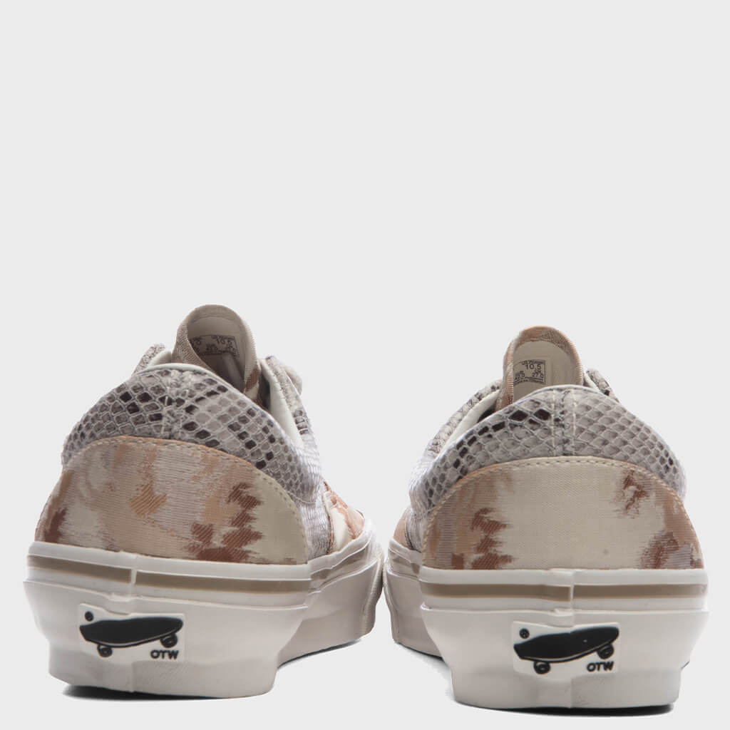 Vista trasera del par de OTW by Vans Era 95 Vibram Floral River Taupe sobre fondo gris claro, con el textil floral beige y tostado en el talón, los paneles de textura tipo red arriba y la placa con la patineta y las letras OTW en la suela