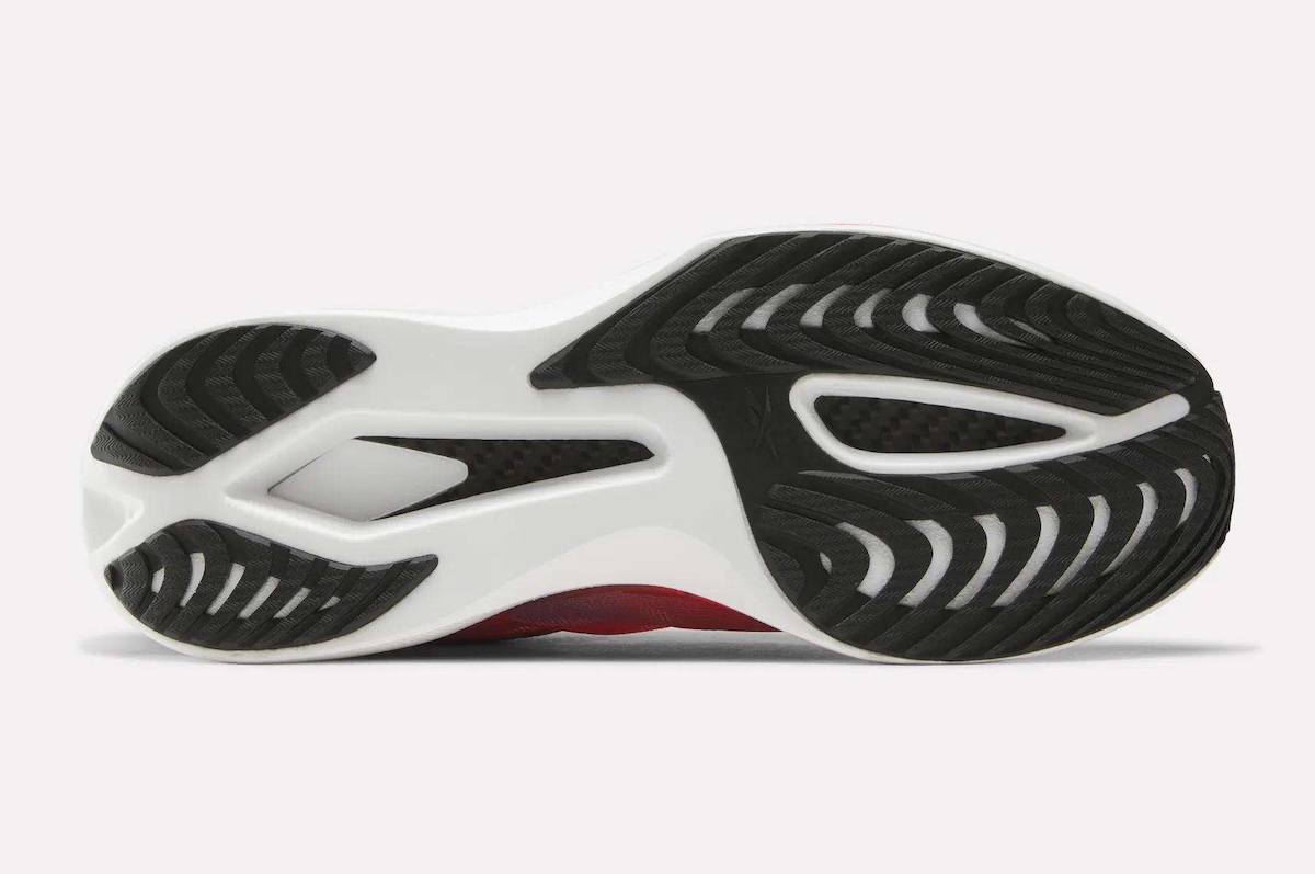 Suela de la Reebok SpeedShifter con tres sectores de goma negra con dibujo en espiga sobre la espuma blanca, y la placa de carbono a la vista en los dos huecos centrales