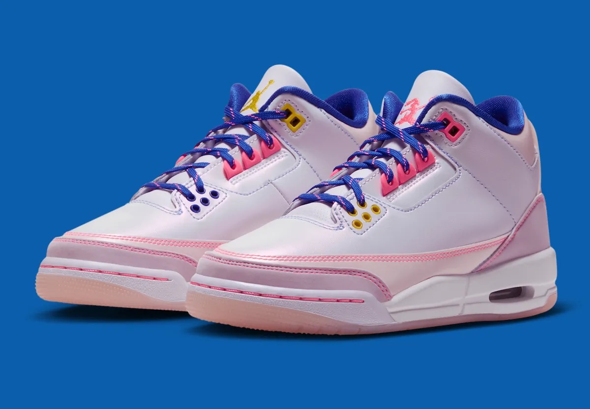 Par del Air Jordan 3 SE Lola Bunny para chicas sobre fondo azul, con upper blanco perlado, overlays rosa claro, costuras y ojales rosa fuerte, cordones azules con motas rosas, interior azul y logos de Jumpman amarillo y de Lola en rosa en las lengüetas