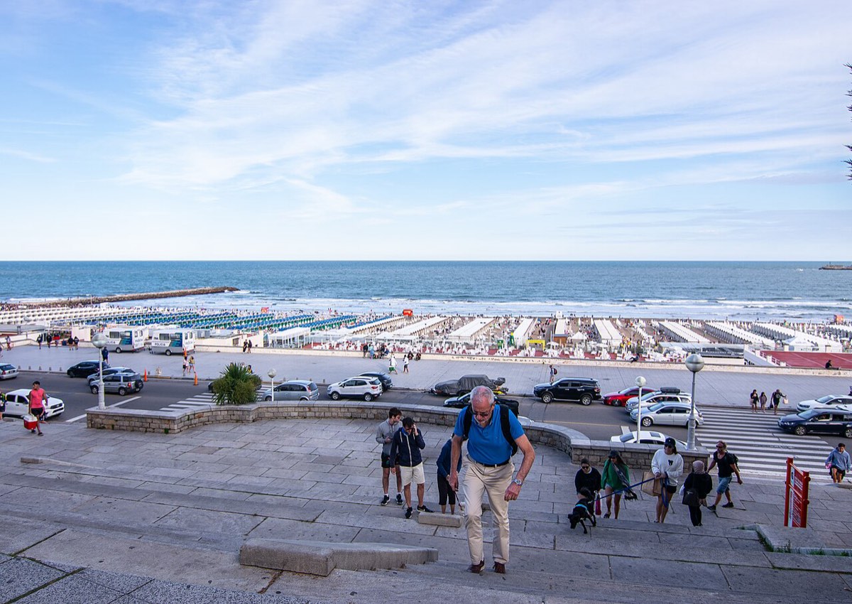 Vista de Playa Grande, en Mar del Plata, desde la escalinata de la costanera: los balnearios, la escollera y el mar abierto bajo un cielo con nubes