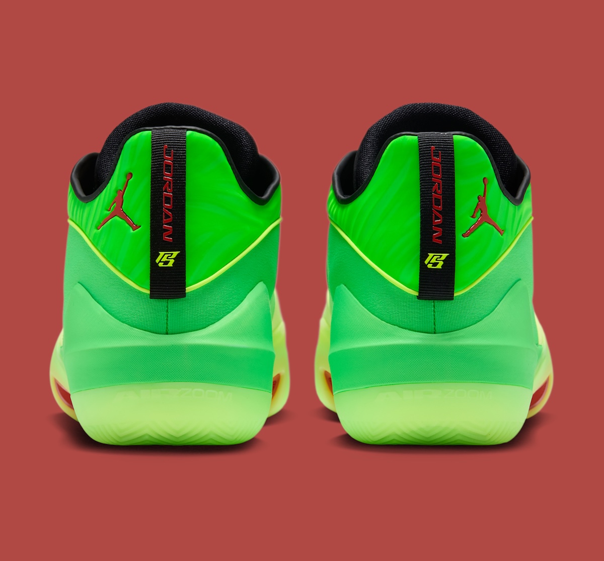 Vista trasera del par de Jordan Triangle Paolo Banchero, con la tira negra del talón que dice Jordan en rojo, el logo personal de Banchero en verde flúor, Jumpman rojo al costado y la palabra Air Zoom en la base verde