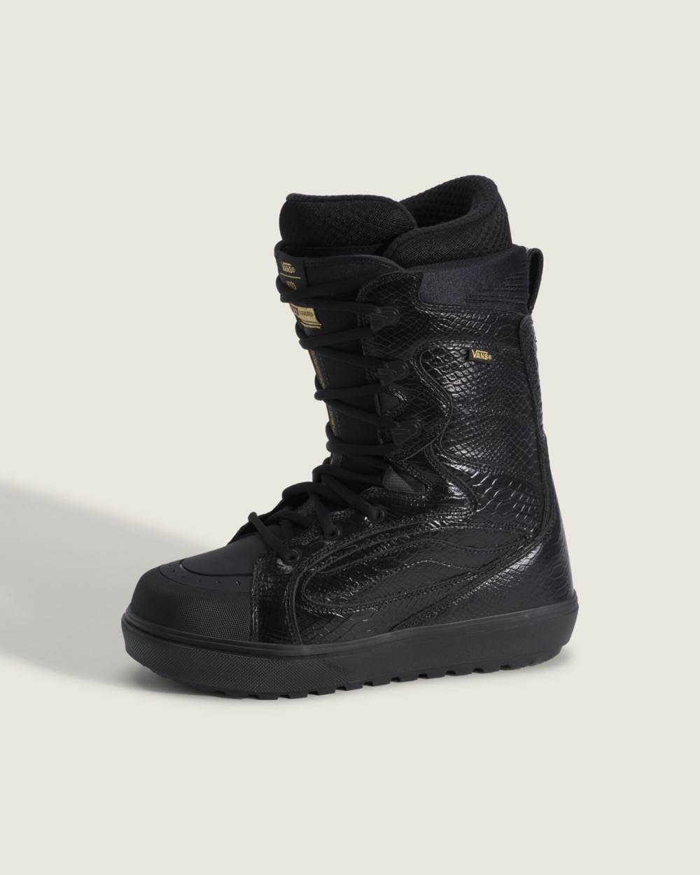 Bota de snowboard Vans Super Standard by Ryo Aizawa de perfil sobre fondo claro, negra con textura de serpiente, cordones negros, etiquetas doradas en la lengüeta y suela negra