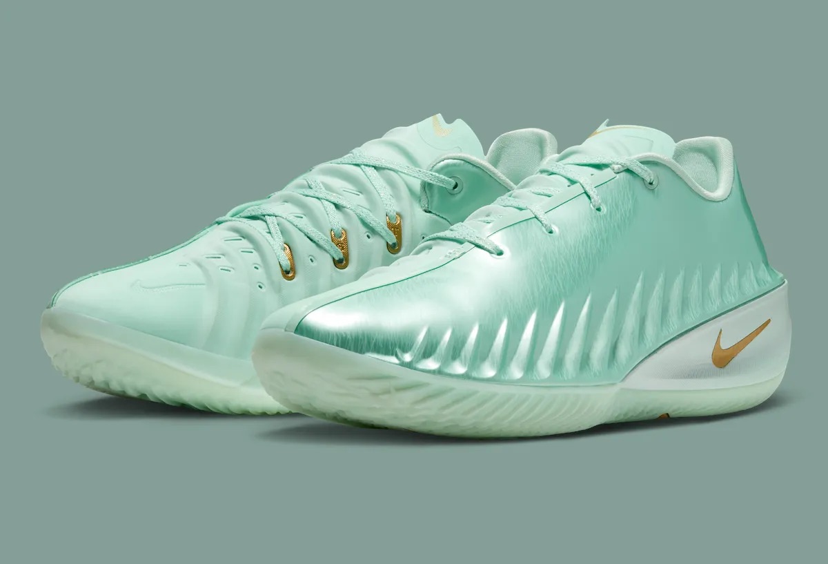 Par de Nike GT Cut 4 Statue of Liberty de Victor Wembanyama sobre fondo verde grisáceo, con upper verde menta metalizado, Swoosh dorado y ojales dorados